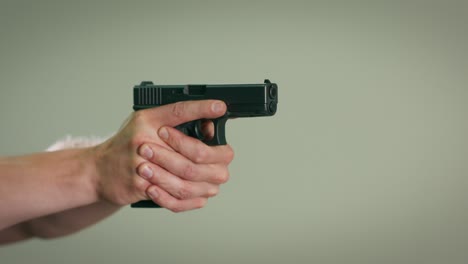 close-up of the hand of a shooting instructor aiming and firing a shot at a target on an indoor training range