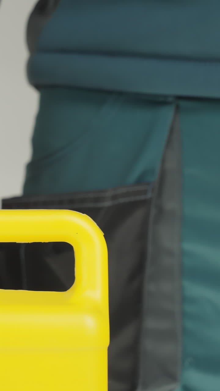 Person wearing gloves handling a yellow container