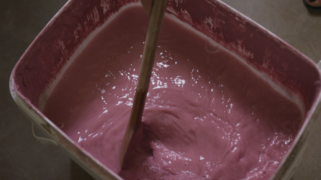 Primo piano di un vasaio che mescola la vernice in un contenitore in uno studio di ceramica