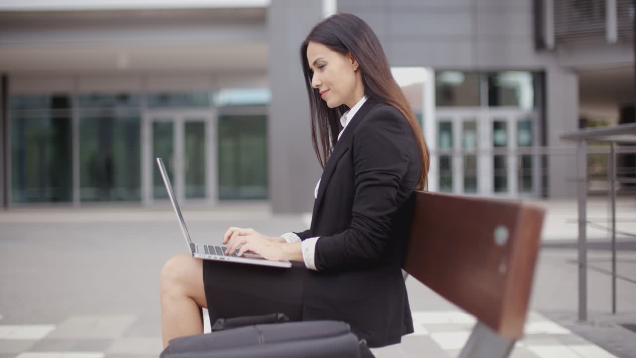 Donna che osserva con un laptop su una panchina