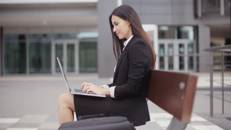 Frau-Schaut-Mit-Laptop-Auf-Bank-Herüber