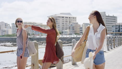 Three-young-women-tourists-on-summer-vacation-walking-on-beach-promenade