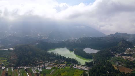 Foggy-mountains-and-Warna-lake-in-Indonesia,-high-altitude-aerial-view