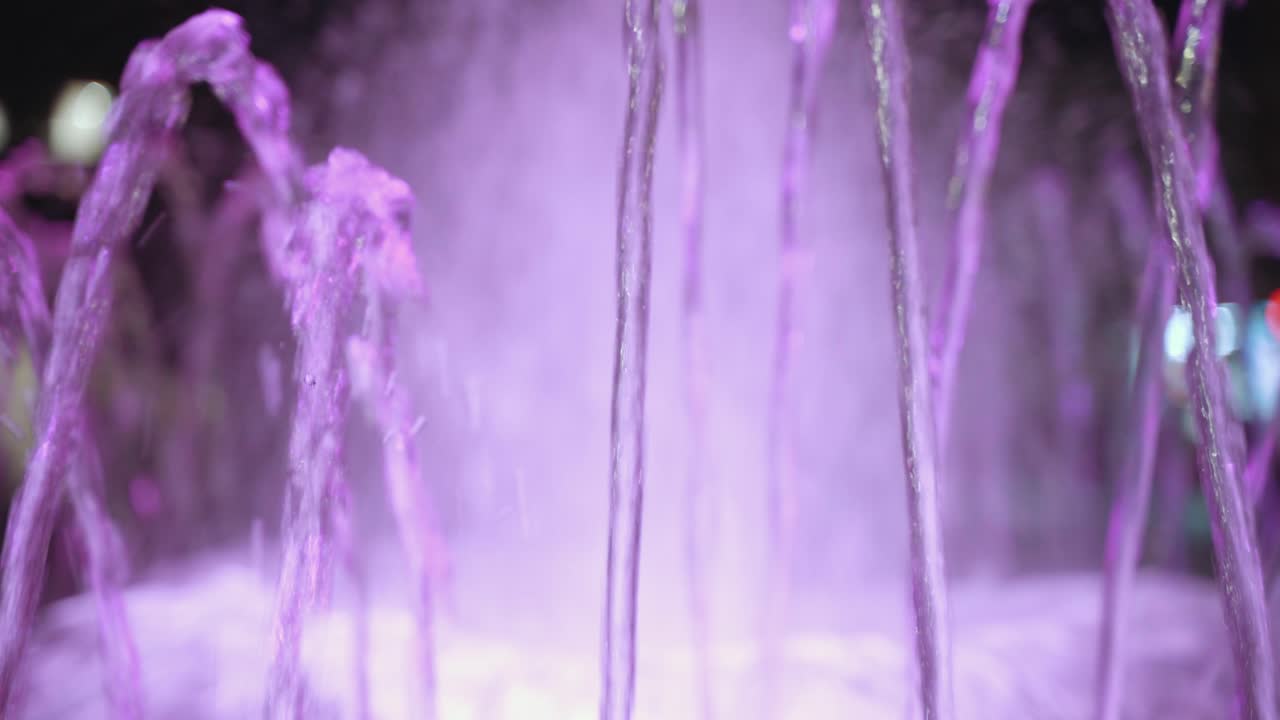 purple water fountain with the cars moving behind. Light flare of the cars