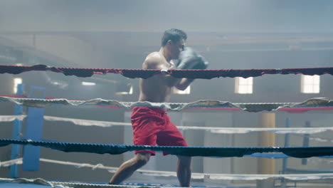 young male boxer doing shadow fight while training