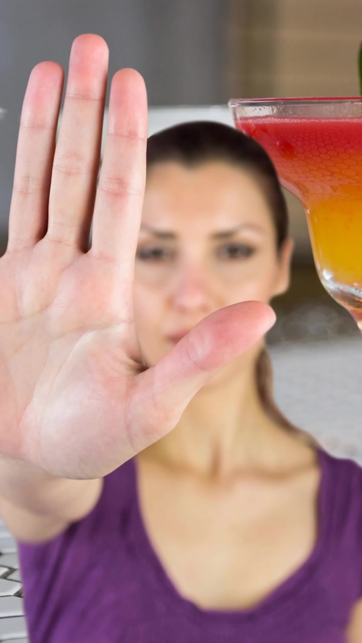 Animazione di una donna caucasica che fa il gesto di stop con la mano, sopra bicchieri da cocktail su un bancone del bar