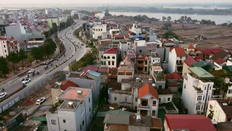 Luftdrohnenaufnahme-Vietnamesischer-Gebäude-Entlang-Einer-Straße-Und-Eines-Großen-Flusses-In-Hanoi,-Vietnam