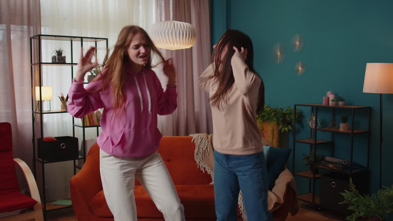 Happy two teenage girls siblings or bloggers couple dancing at home having fun enjoying trendy dance