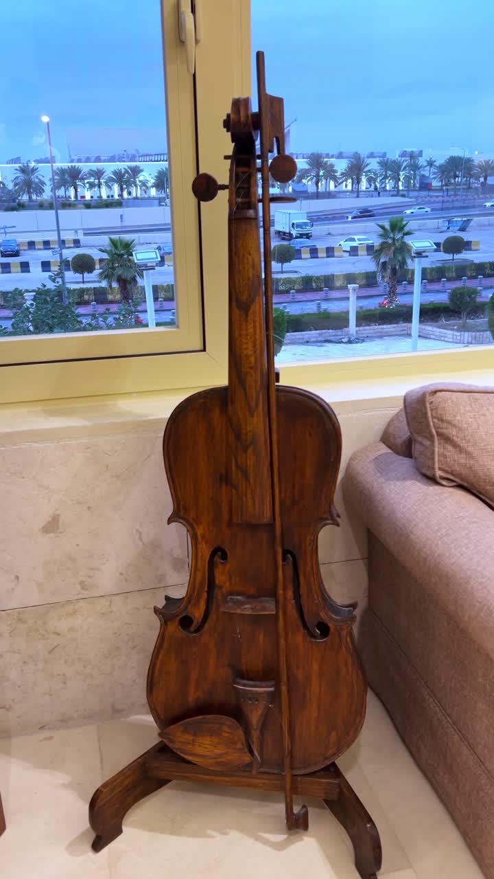 Vertical 4K close-up of a vintage wooden cello placed indoors near a window. Ideal for music-themed videos, interiors, artistic mood, or background scenes in film and decor projects.