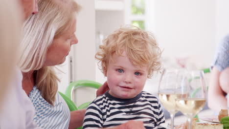 grandmother playing with grandson as they sit at table for family meal