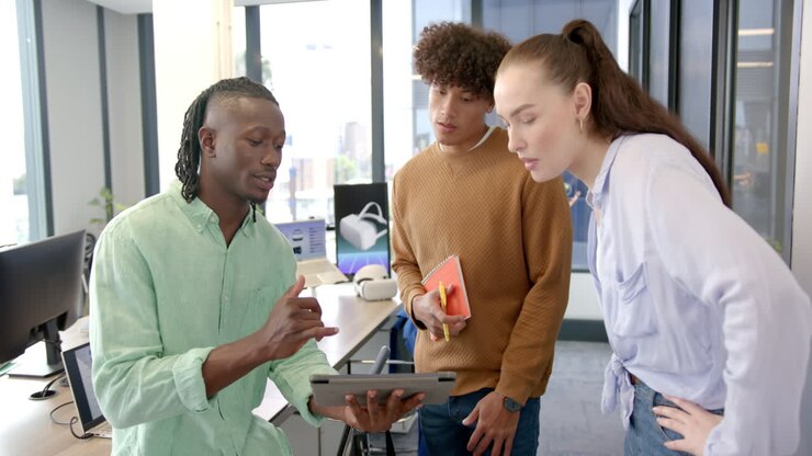 Discussing project details, diverse team collaborating using tablet in modern office