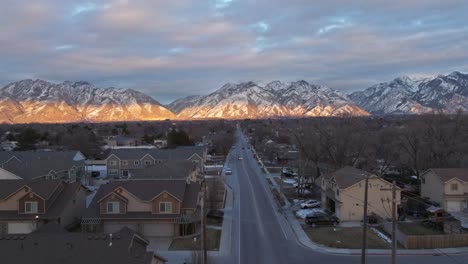 Flying-over-streets-facing-towards-mountains-at-sunset-in-Midvale-Utah-neighborhood