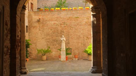 shot of a religious statue surrounded by historic architecture in urbino, italy at daytime