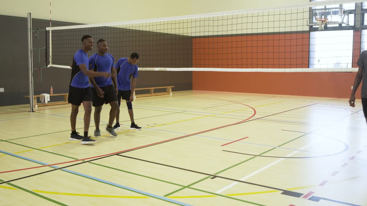 Equipes masculinas diversas de vôlei caminhando para a rede no ginásio após a partida, apertando as mãos, segurando uma bola de vôlei.