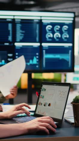 vertical video focused businesswoman analyzing graphs and data on laptop at the table