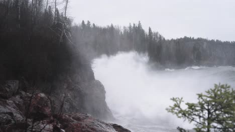 Rough-storm-waves-crash-against-coastal-cliffs-during-dark-gloomy-weather,-slow-motion