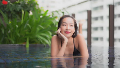 beautiful asian girl daydreaming in wellness hotel swimming pool slomo