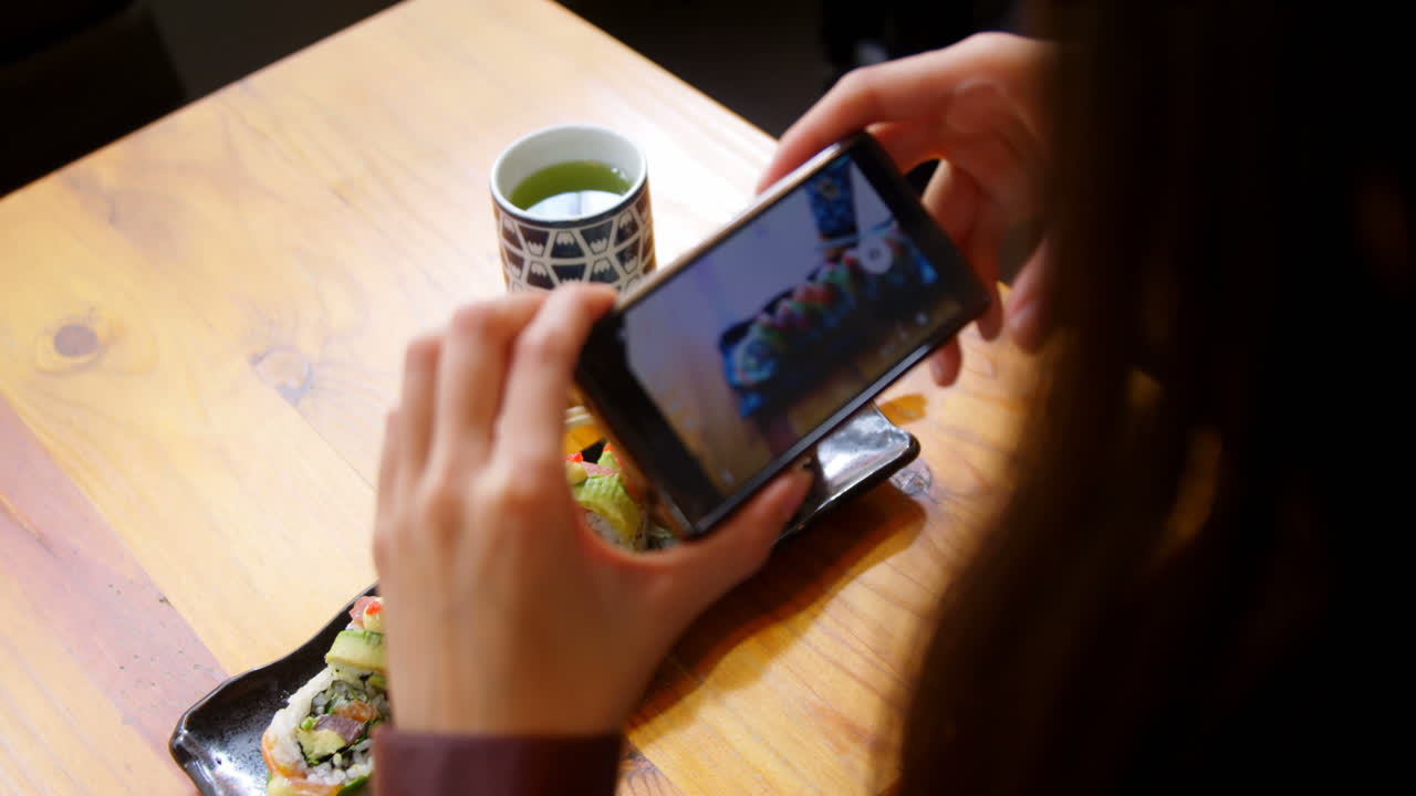 mujer tomando fotos de sushi con teléfono móvil 4k