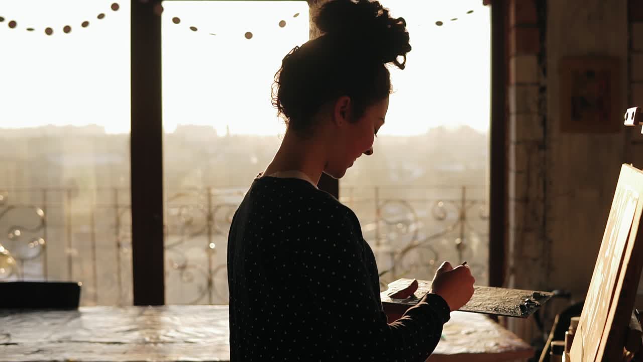 joven artista dotada sonriendo mientras trabaja en la creación de algo maravilloso. pintora profesional trabajando en un estudio de arte.