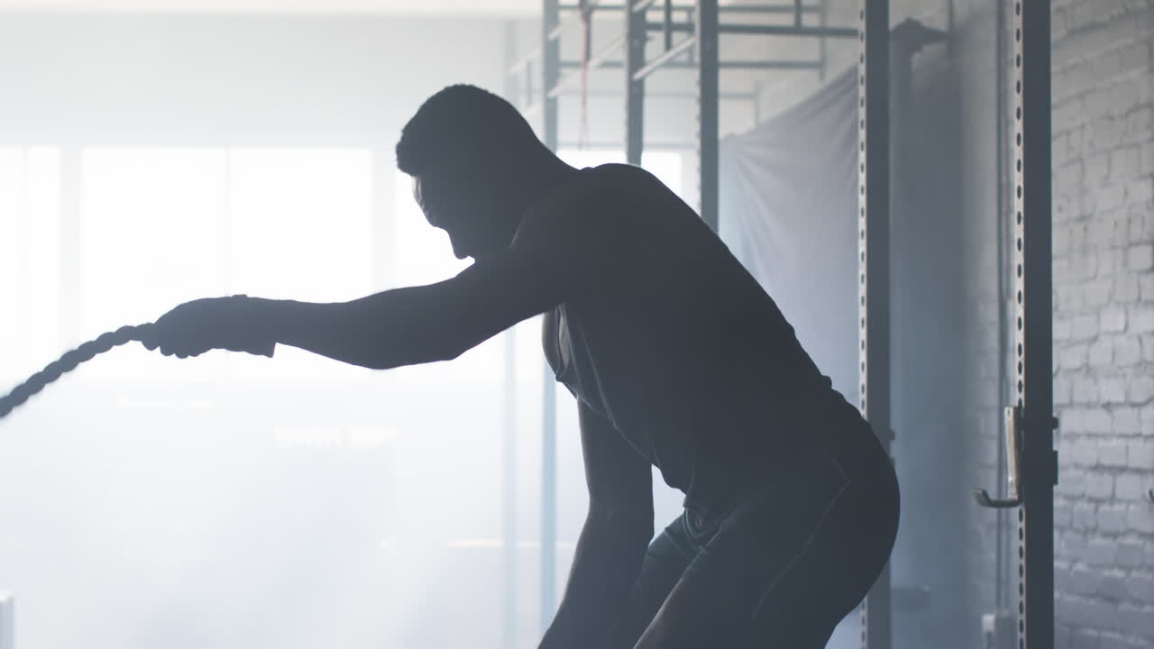 Exercising with battle ropes, man training in gym for strength and endurance
