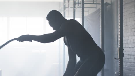 exercising with battle ropes, man training in gym for strength and endurance