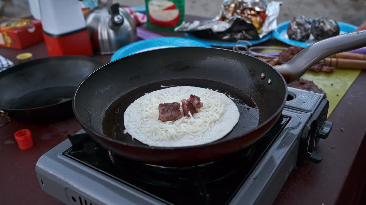 부드러운 핸드헬드 실시간, 야외 쿡탑 그릴에서 스테이크와 야채 케사디아 요리, 캠프장에서 프라이팬