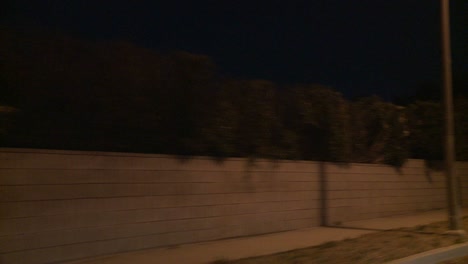 un automóvil viaja a lo largo de una calle sinuosa en la noche en los ángeles california como se ve a través de la ventana trasera en un ángulo 1