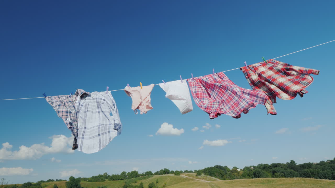 바구니를 든 여자는 밧줄에 젖은 옷을 걸고 있는 것처럼 보입니다 4k 비디오