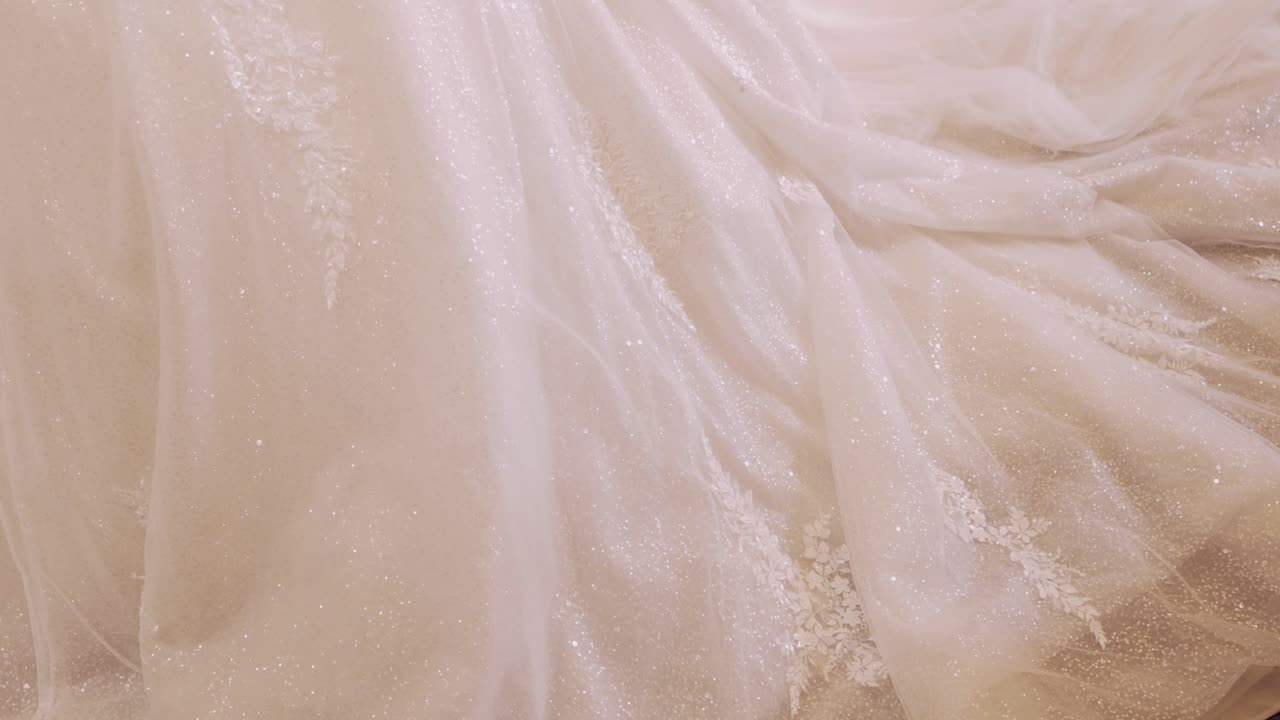 Close up of sparkling white lace wedding gown fabric with soft elegant draping