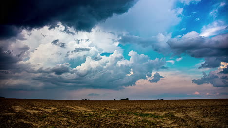 dark clouds and a rainstorm over farmland fields in the countryside - time lapse