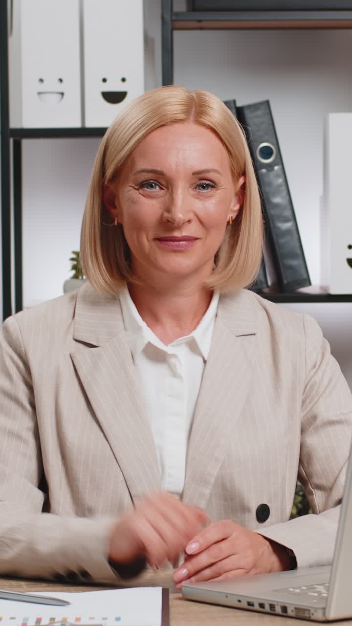 Portrait of mature businesswoman in suit looking at camera after using laptop at home office desk