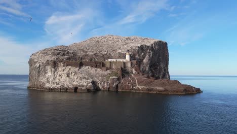 Aerial drone footage of Bass Rock, an island off the coast of North Berwick, Scotland, in the warm summer sunshine. North Sea, rugged cliffs, seabird colonies.