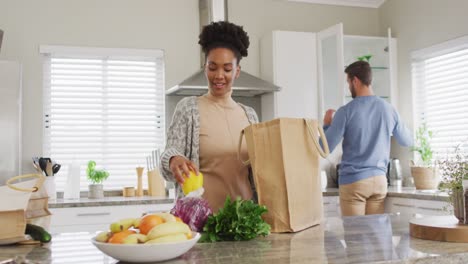 video de una mujer afroamericana desempaquetando comestibles en la cocina