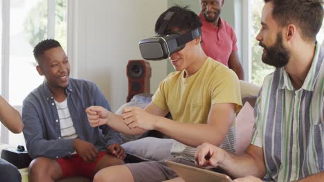 happy diverse male friends using vr headset and talking in living room