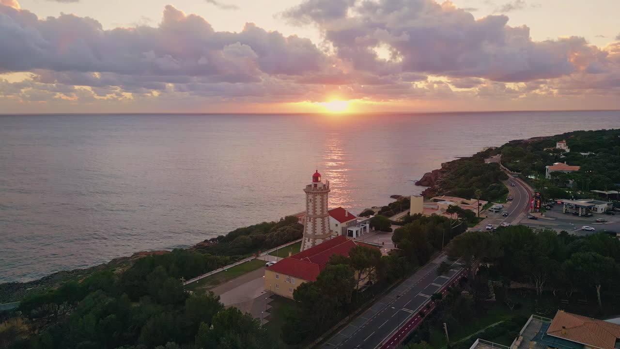 Vista aerea di un faro costiero al bagliore del tramonto. Sera serena che avvolge l'oceano calmo.