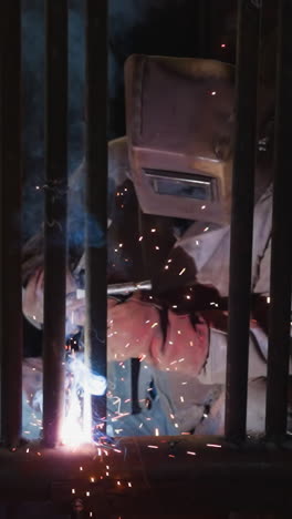 worker in protective uniform welds heat exchanger pipeline grid for boiler house slow motion. bright sparks and light smoke over joined iron tubes at plant