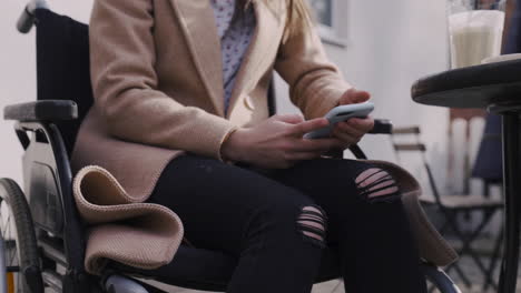 close up of an unrecognizable disabled girl in wheelchair using mobile phone