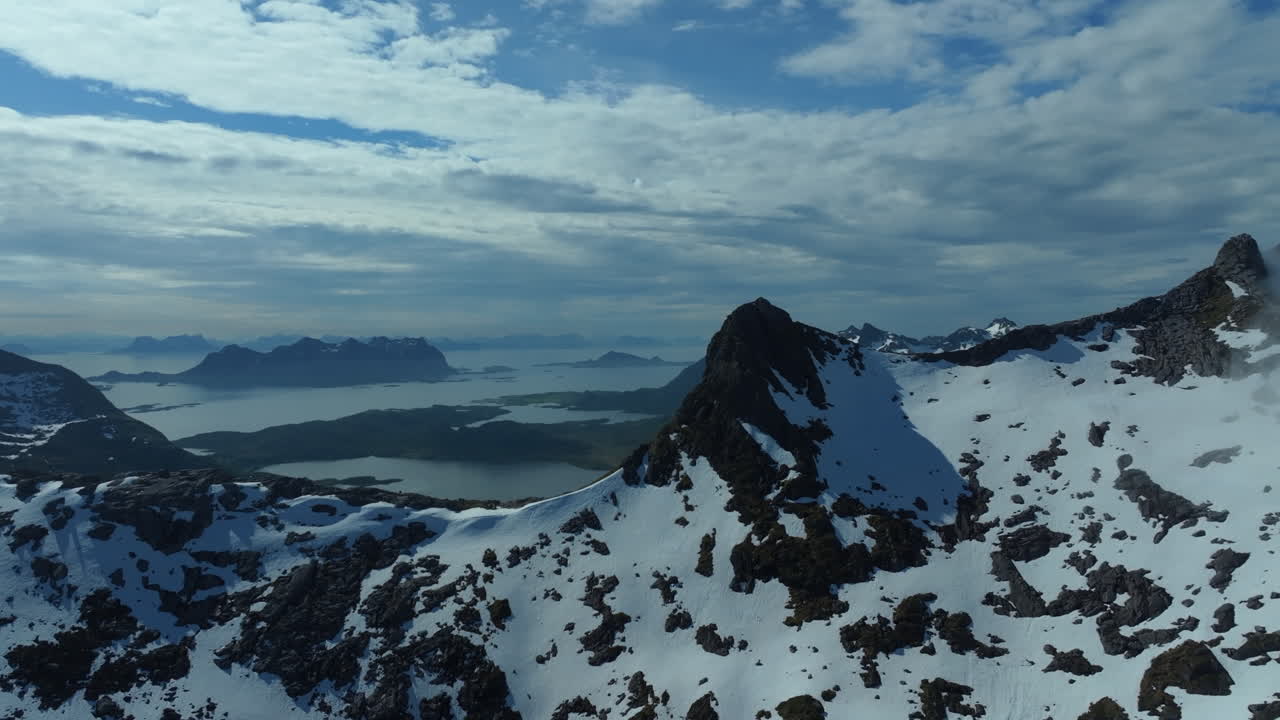 Beautiful aerial view of the Lofoten Islands mountains partially covered with snow overlooking the sea and other islands