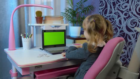 Child-girl-studying-homework-distance-education-on-laptop-webcam-online-lesson-at-home,-green-screen