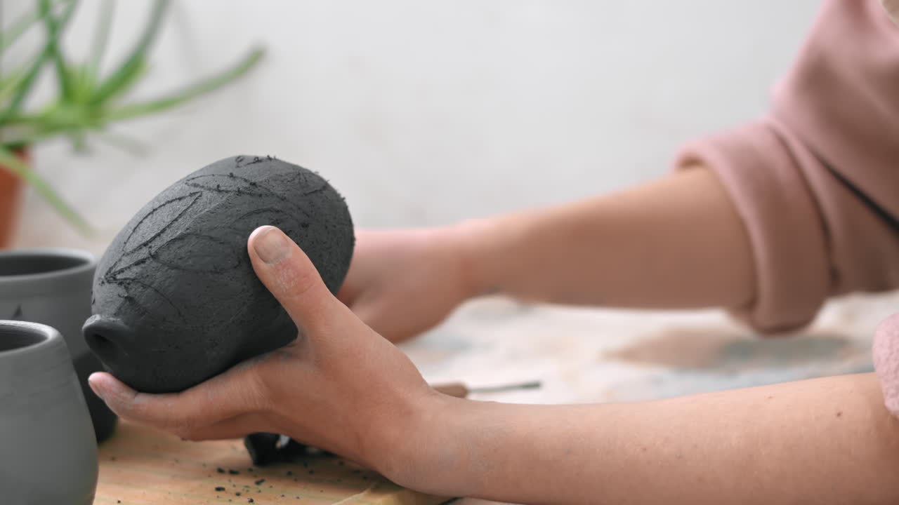 The master of sculpting pottery working in a studio. Cuts holes in fresh pottery