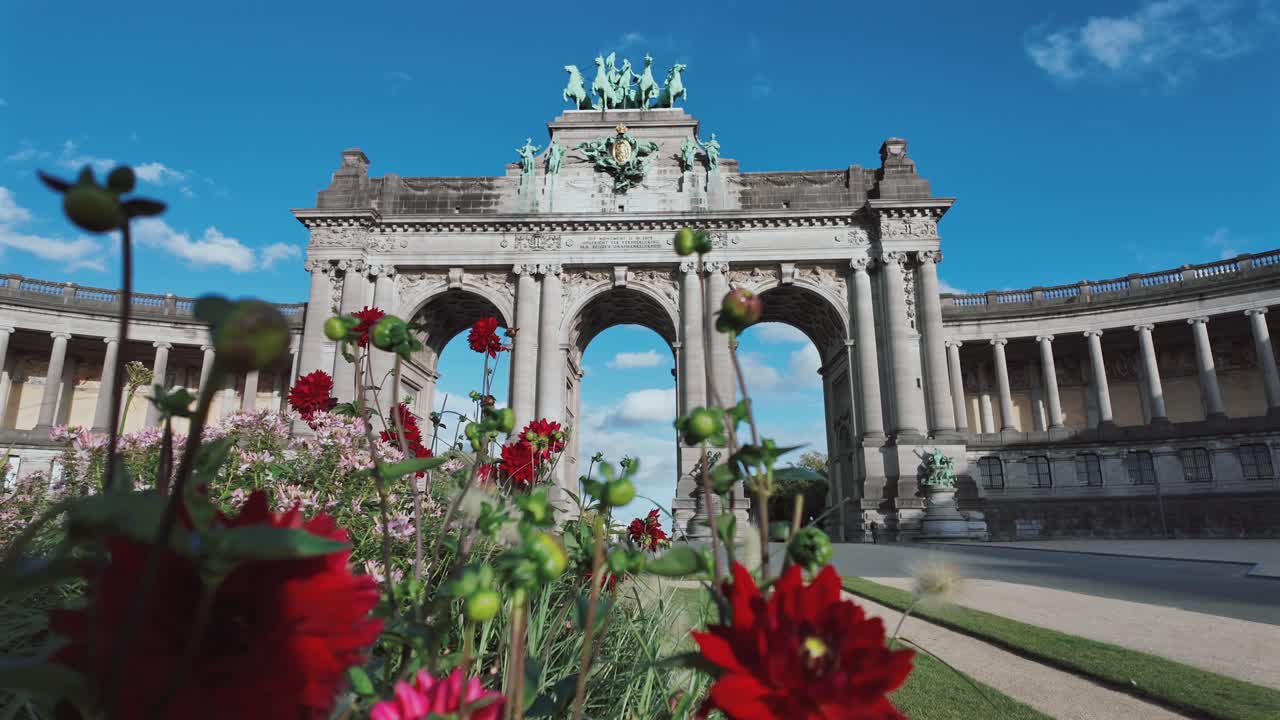 Low angle view of Cinquantenaire Arch with red flowers in foreground