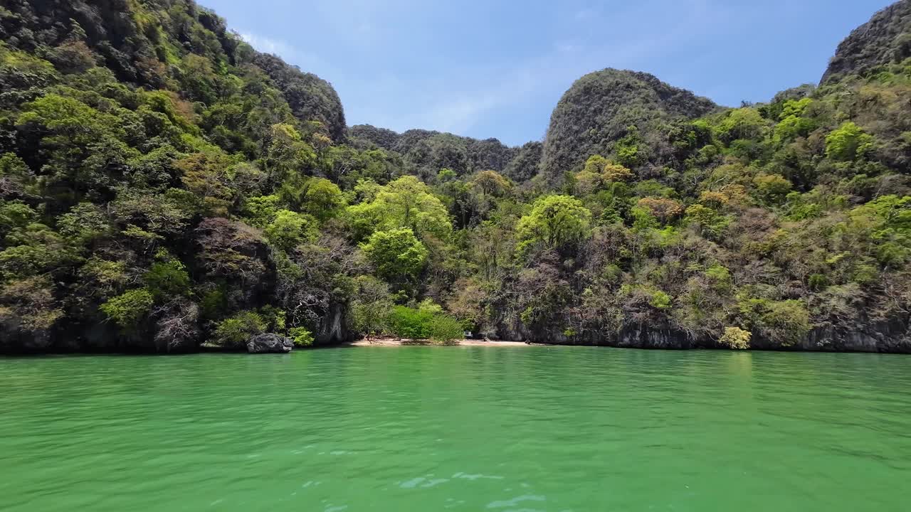 A scenic boat ride through towering limestone cliffs in Phang Nga Bay, Phuket, Thailand, featuring tropical waters, dramatic karst formations, and a popular travel destination