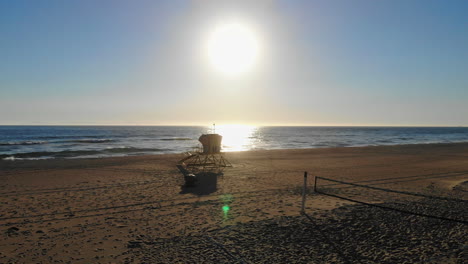 tracking fly by over empty volleyball courts and nets with beautiful ocean sunset in background at huntington beach, southern california with aerial 4k drone