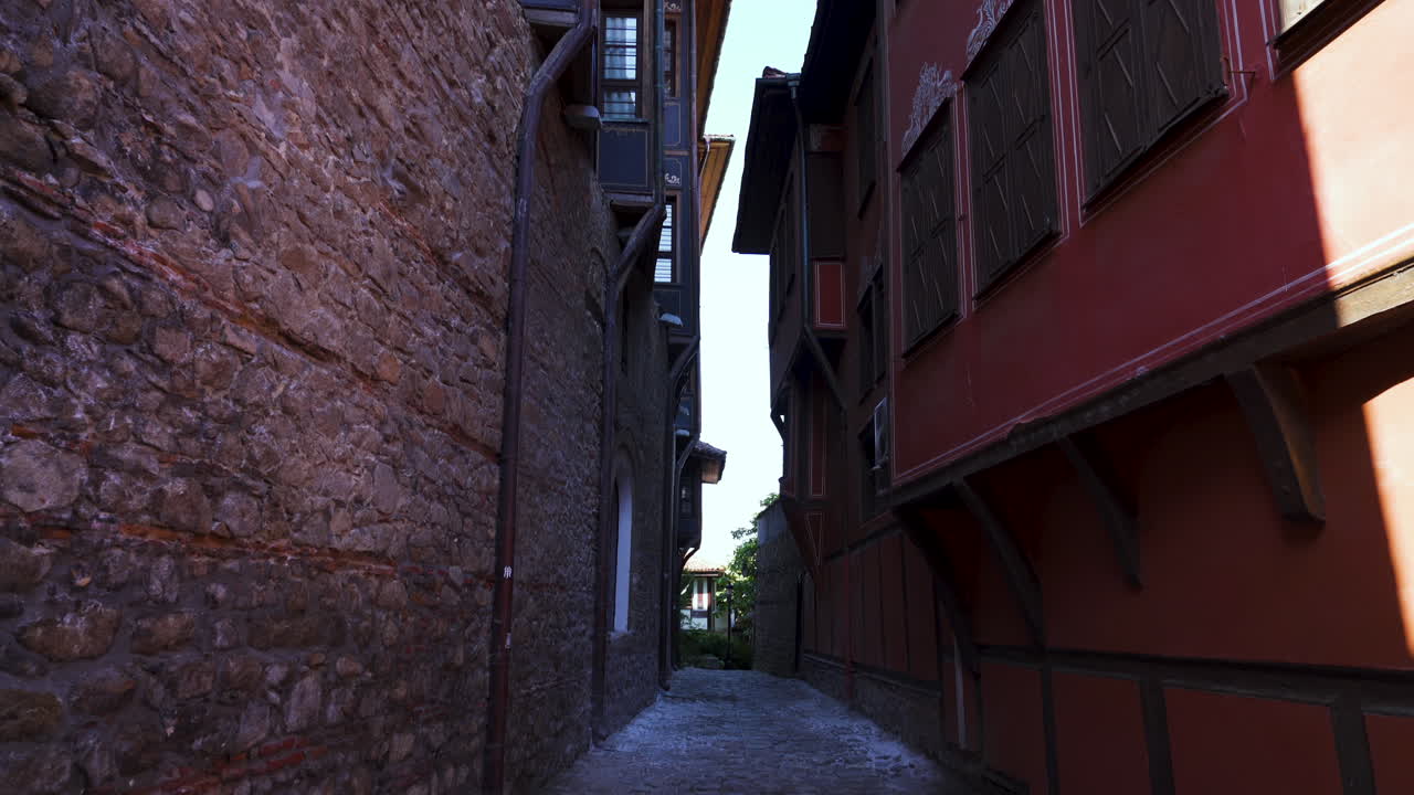 Slow POV push-in over the facade of a traditional Revival-era house in Plovdiv’s Old Town, Bulgaria. The historic architecture features colorful wooden details and spring atmosphere
