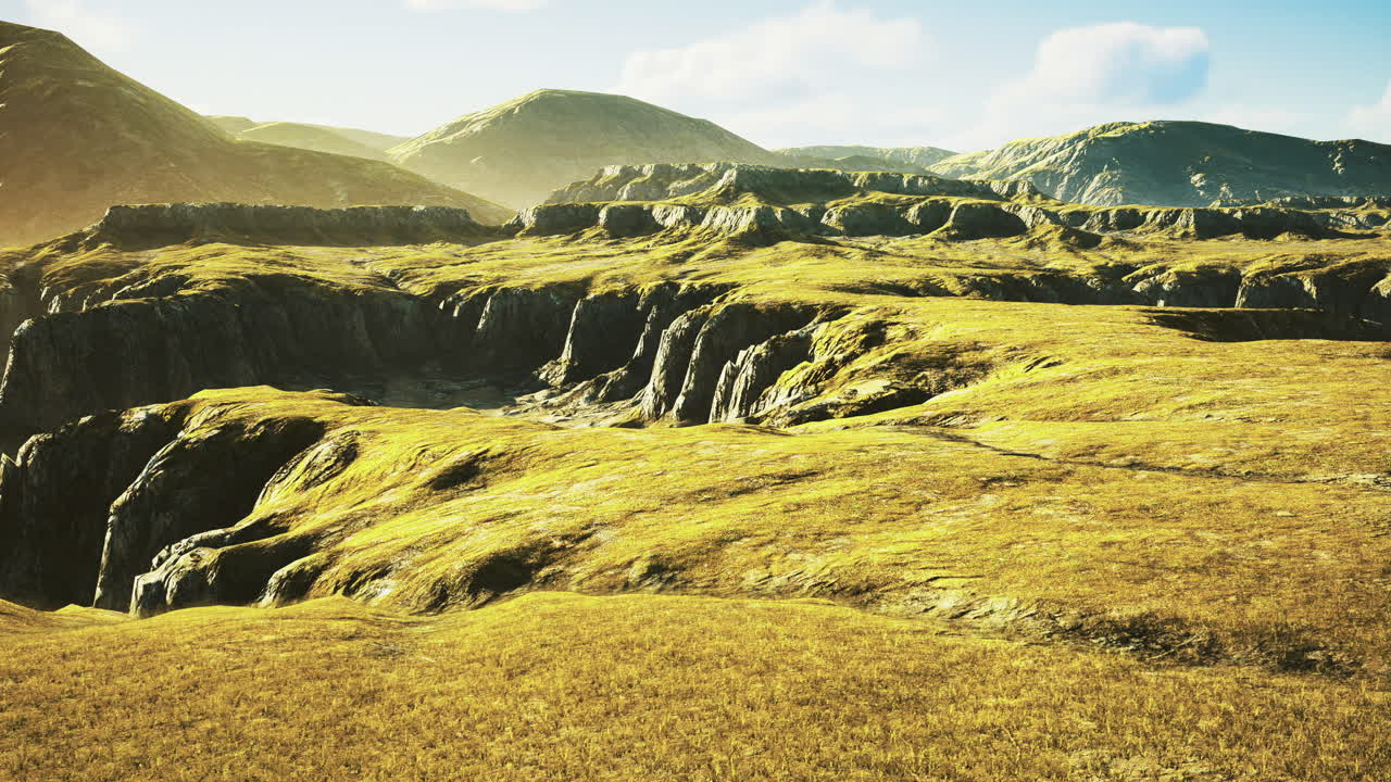 Vast grassy landscape under a clear blue sky with distant mountains in sunlight