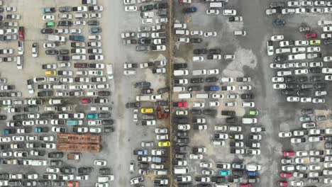 vista aérea hacia abajo vista sobre estacionamientos al aire libre con muchos vehículos de tipo y color aleatorios.