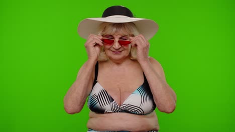 Senior-woman-tourist-wearing-red-sunglasses,-looking-at-camera-and-smiling-on-chroma-key-background