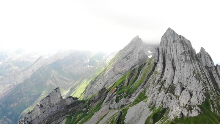 Drohnenflug über den Felswänden des Schäflergrats in Appenzell, Schweiz, abseits des Altenturm-Gipfels an einem bewölkten Sommertag mit Blick auf einen der beliebtesten und doch gefährlichsten Wanderwege der Schweiz.