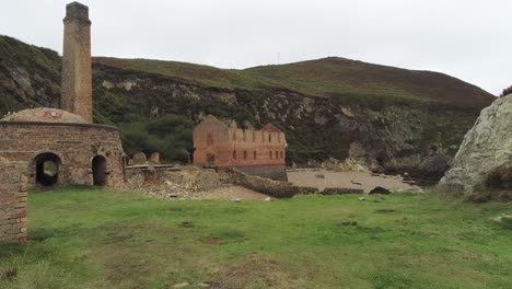 Porth-Wen-aerial-low-forward-view-abandoned-Victorian-industrial-brickwork-factory-remains-on-Anglesey-eroded-coastline