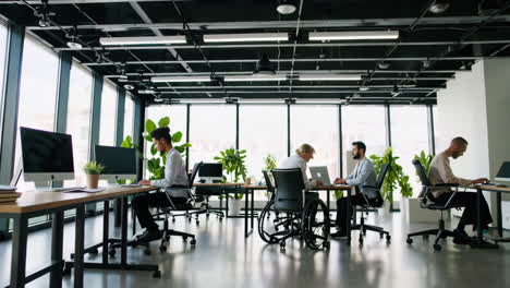 diverse group of people working in a modern open-plan office including an individual using a wheelchair